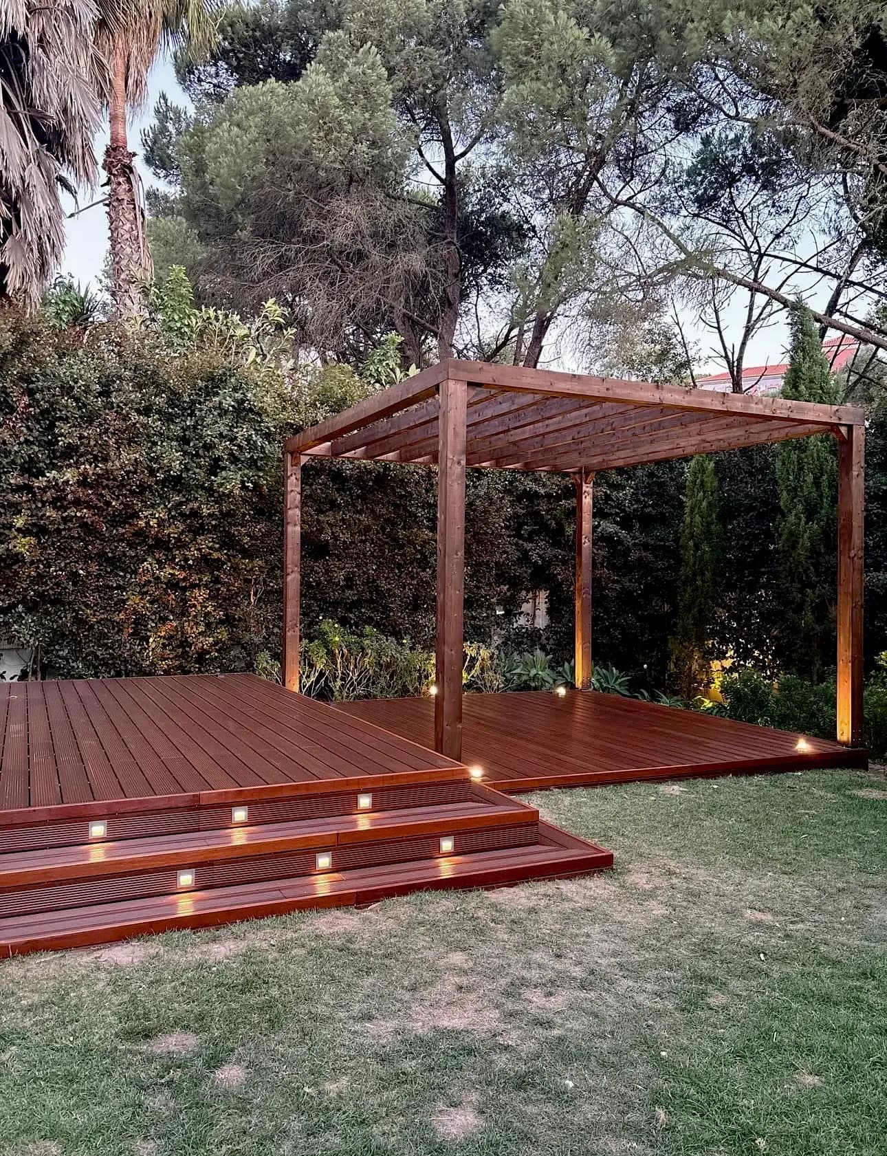 Pérgola com deck em madeira e iluminação integrada executada pela Arawood Garden.