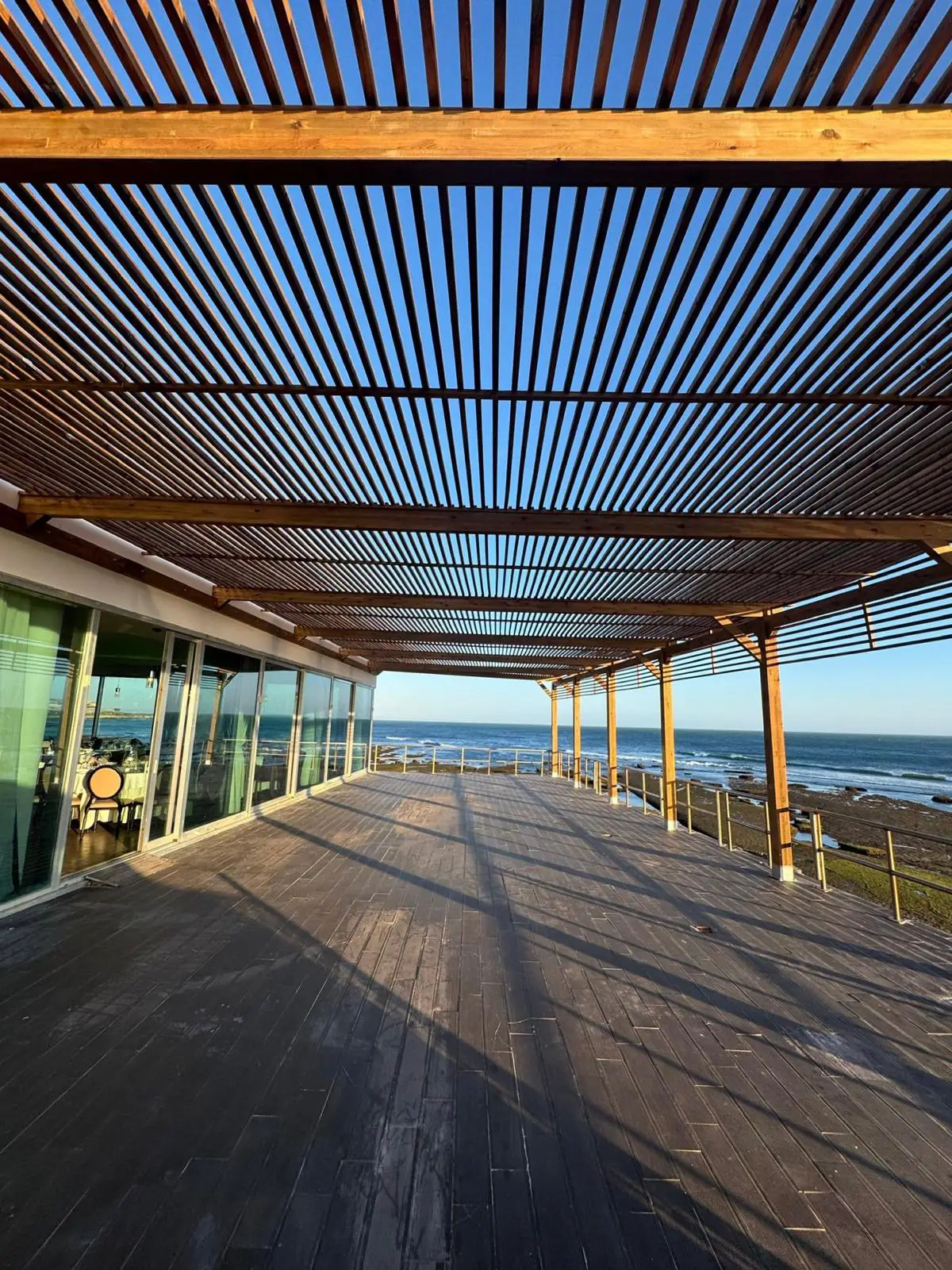 Pérgola e deck em madeira numa zona exterior com vista para o mar, executados pela Arawood Garden.