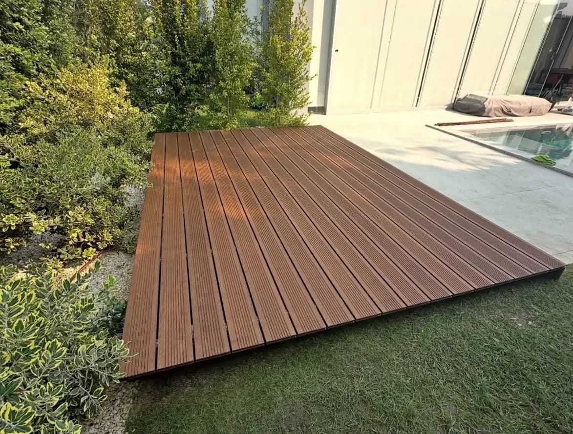 Deck em madeira integrado numa zona exterior ajardinada junto à piscina, executado pela Arawood Garden.