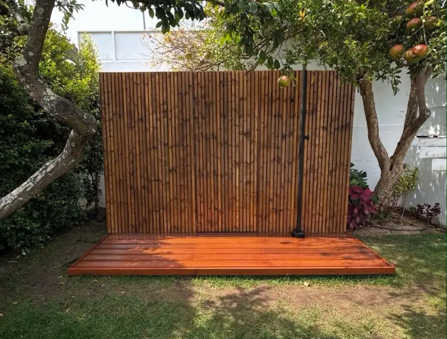 Revestimento vertical em madeira integrado com deck num jardim, executado pela Arawood Garden.